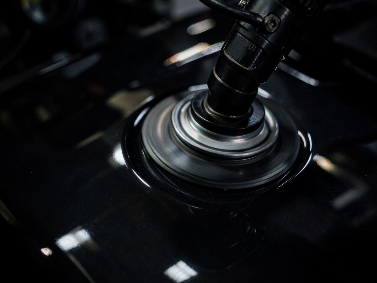 Machine polisher performing paint correction on dark automotive paint in Utah County